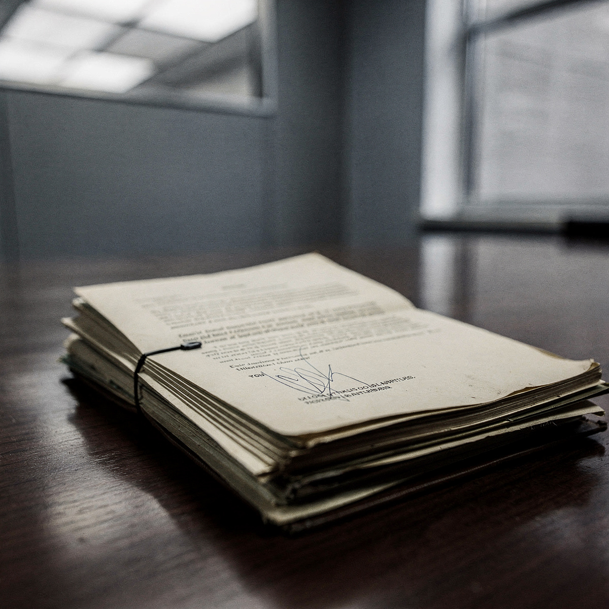 A legal document, likely a court ruling or legal brief, rests on a polished, dark wood table in a quiet, institutional setting.