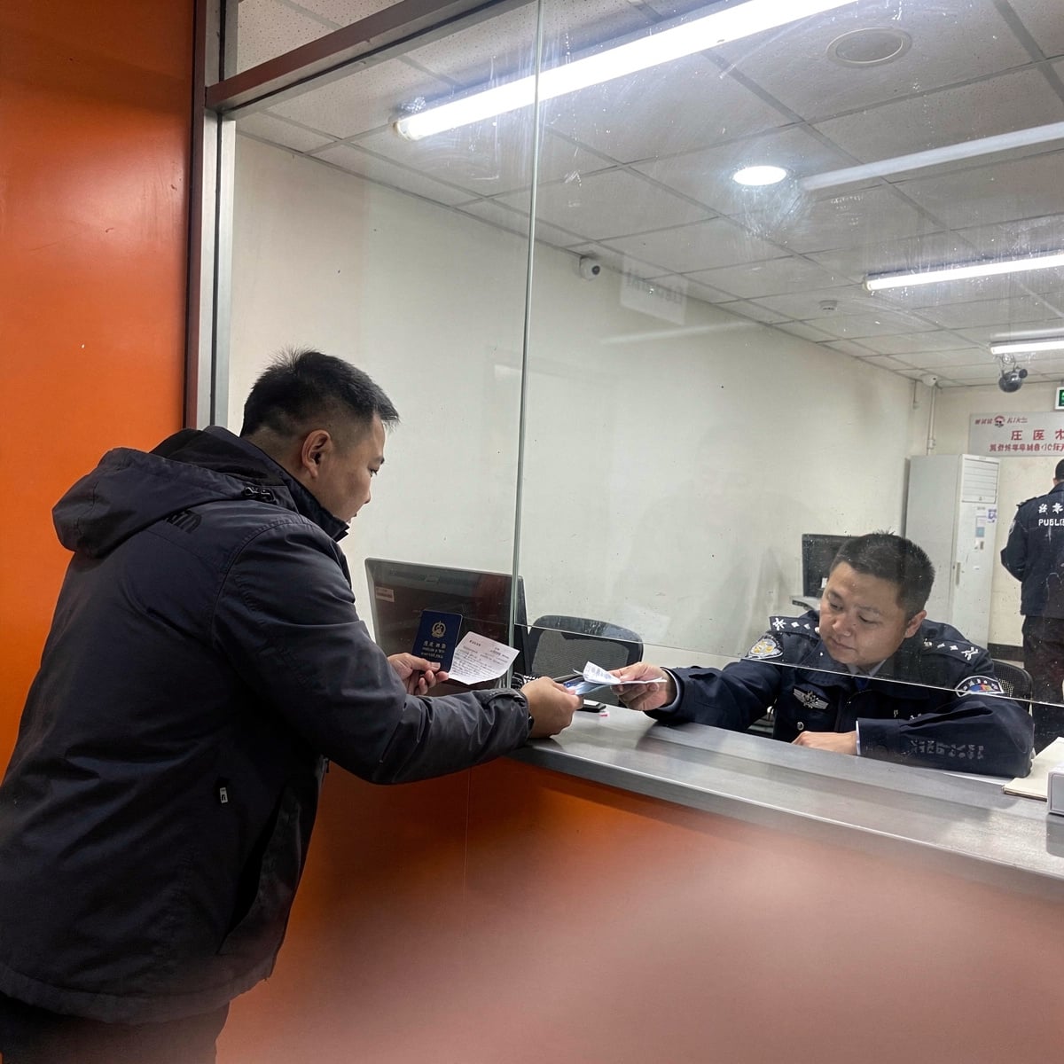 A traveler in a public security service window in China, registering their accommodation.