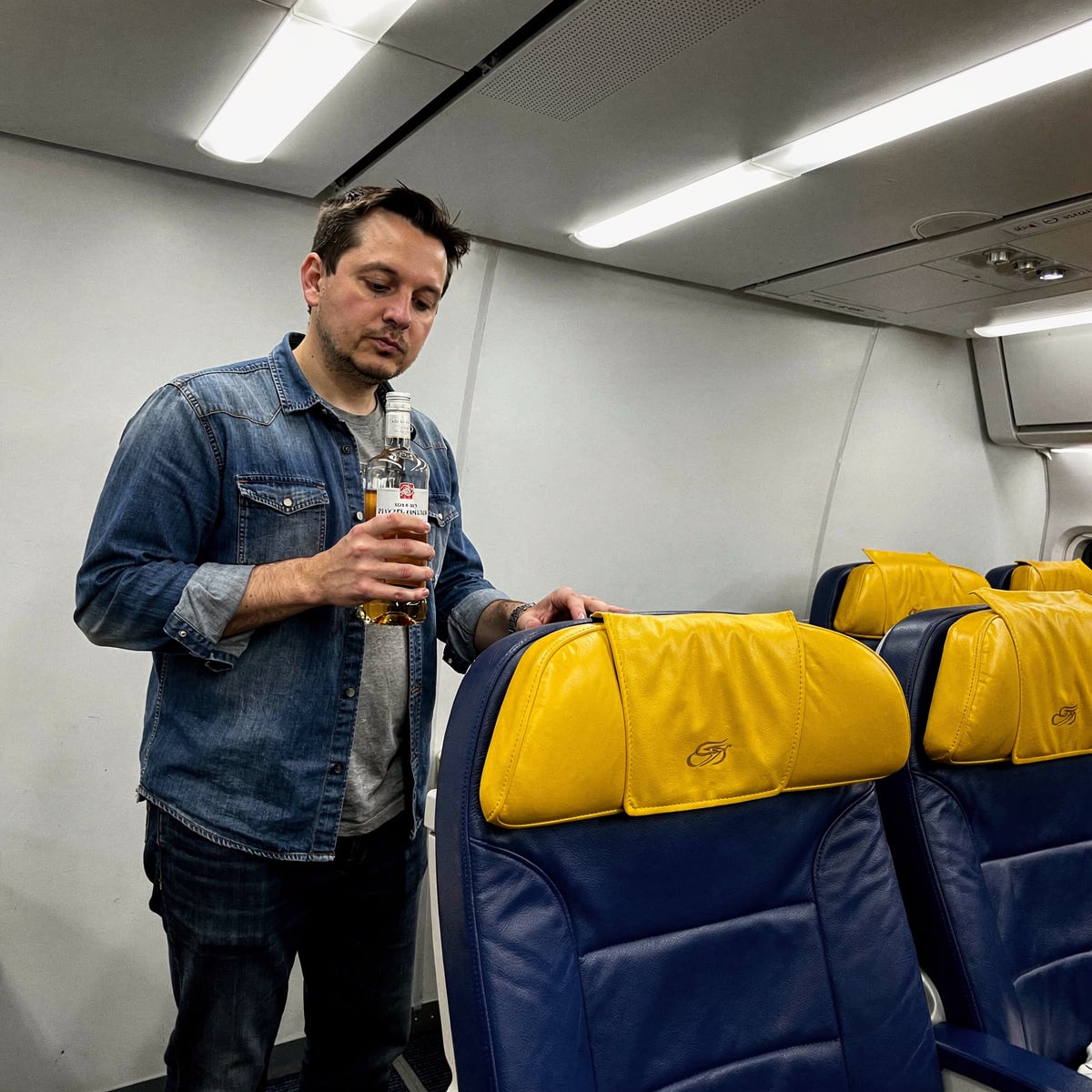 An airline cabin interior, brightly lit, during a routine flight.