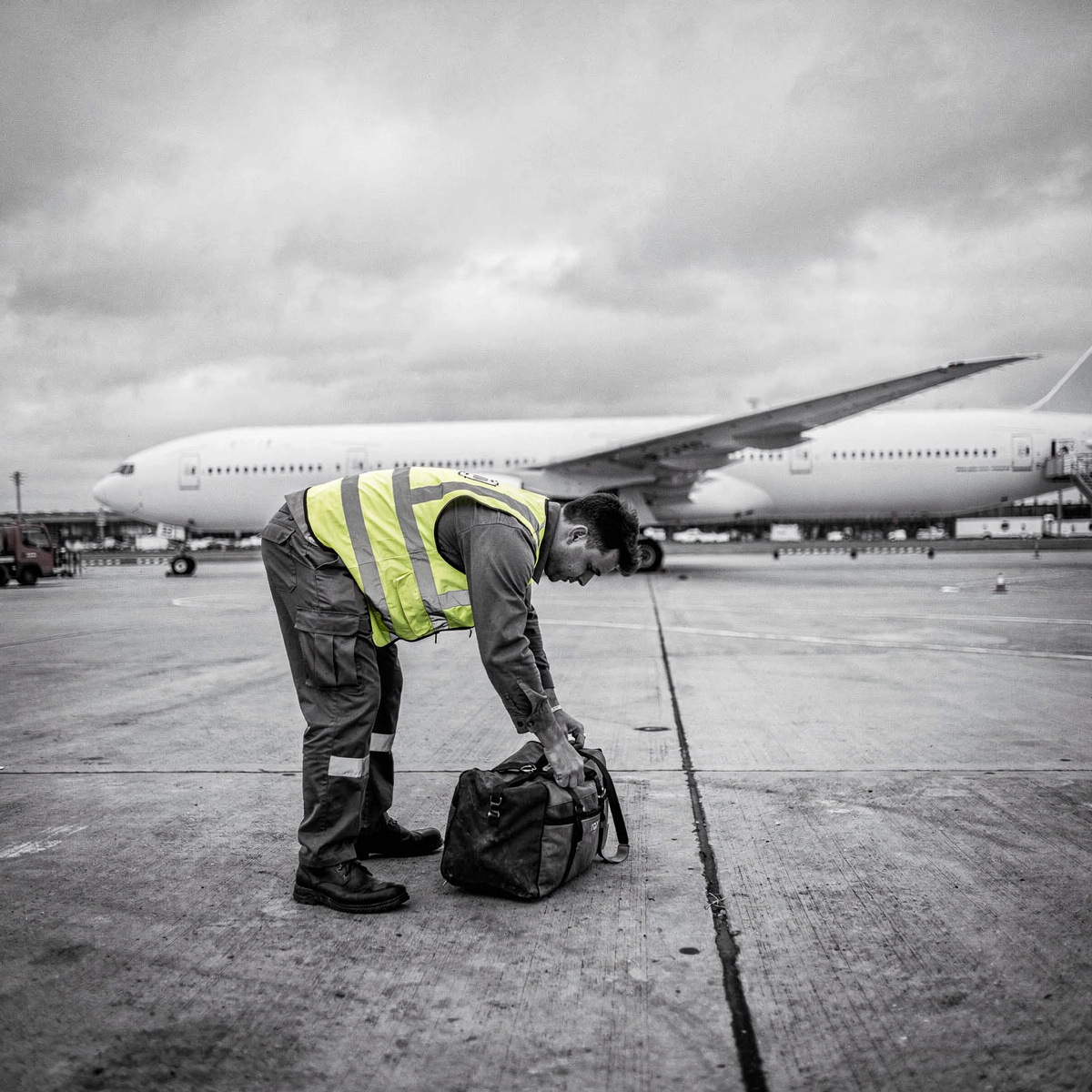 An aircraft at the stand under overcast skies, ground crew working around the nose gear.