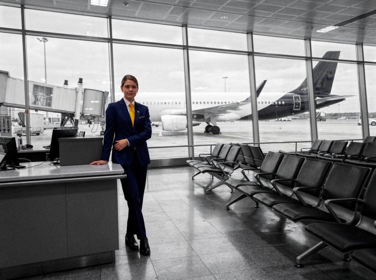 An empty departure gate at a major European hub airport during the day, with an Airbus A320 family aircraft visible through the glass.