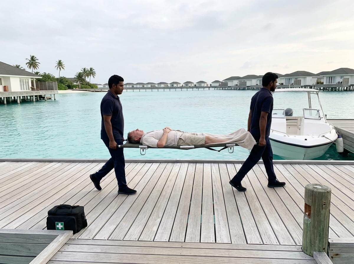 Traveler on a stretcher carried along a Maldives jetty toward a waiting boat (ATC Intel)
