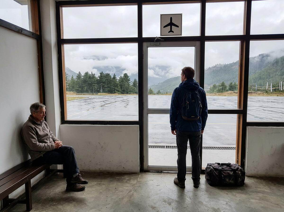 Traveler waiting at a misty Paro airport gate after a weather cancellation (ATC Intel)