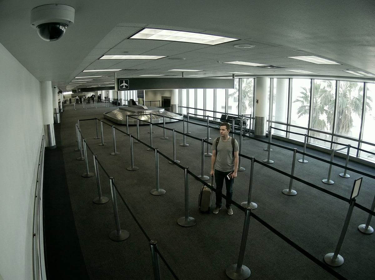 Traveler with suitcase in a US immigration queue at LAX for a short connection (ATC Intel)